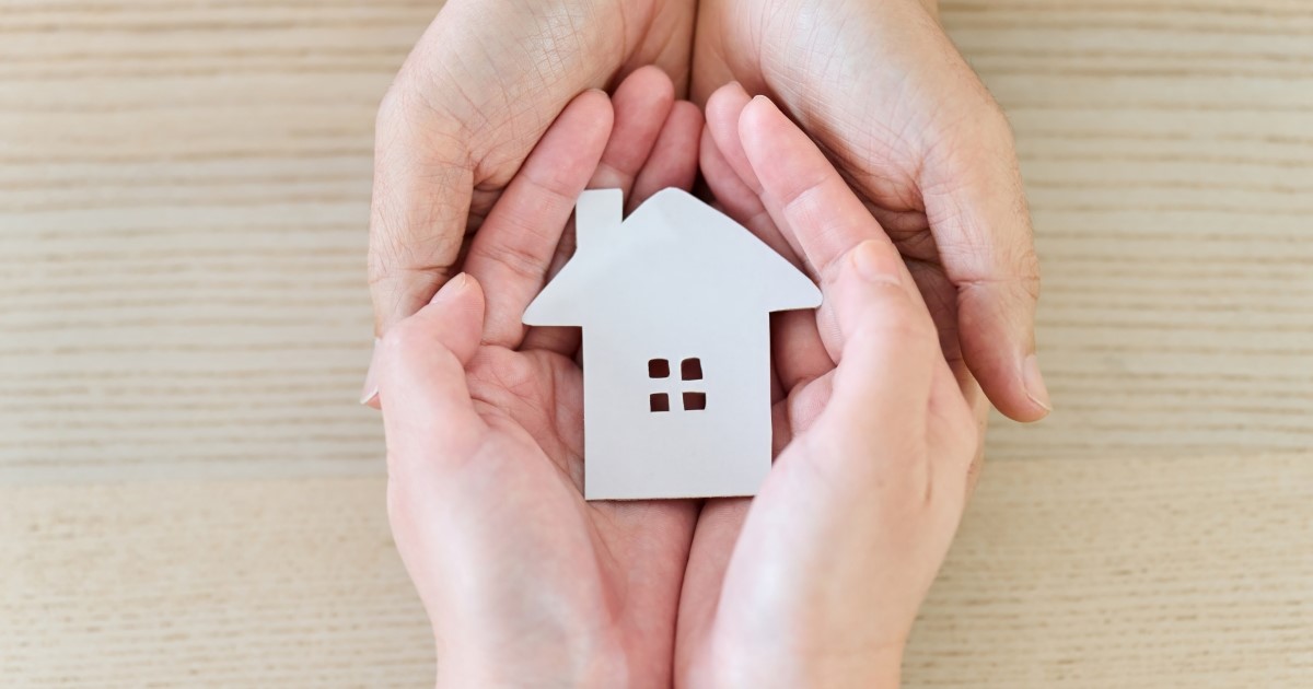 Image de mains tenant une petite maison en papier