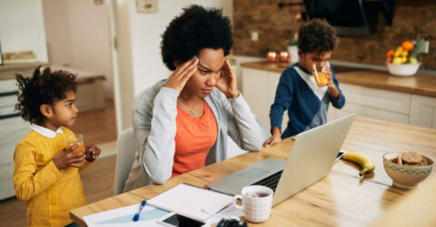 Image montrant une mère débordée devant un écran d'ordinateur et entourée de ses deux enfants